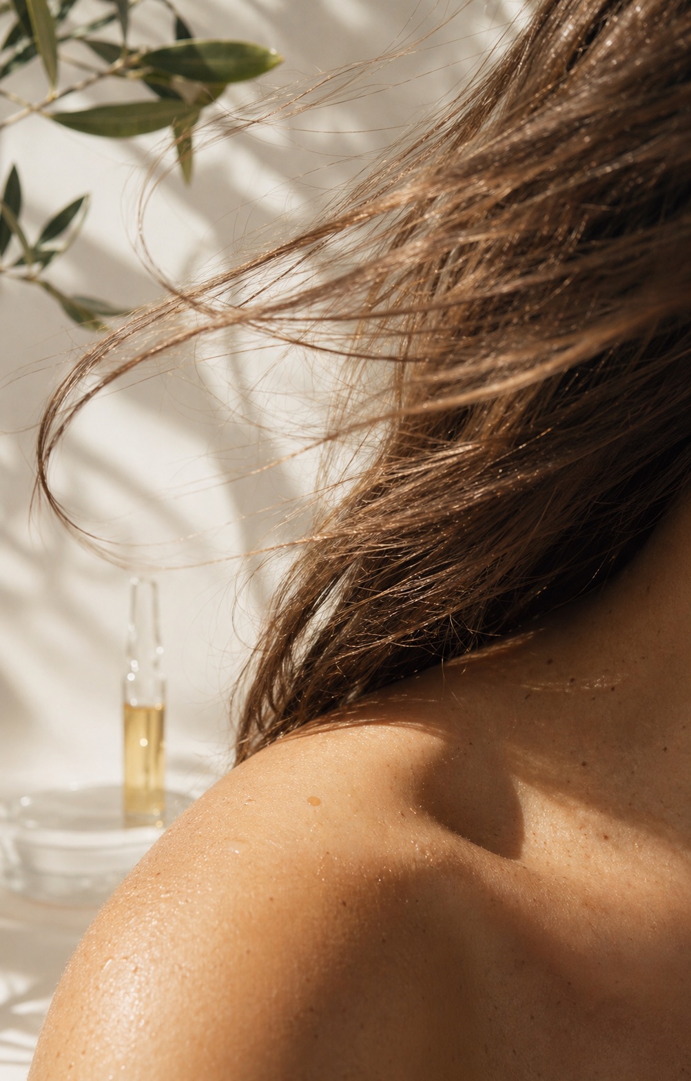 Sunlit close crop of healthy hair moving across luminous skin.